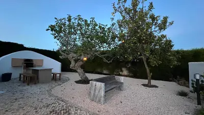 a table and a bench next to a tree at Dad's Villa in Lagos