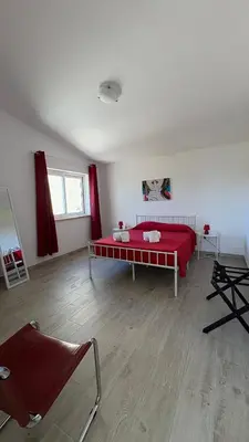 a bedroom with a red bed and some chairs at Dad's Villa in Lagos