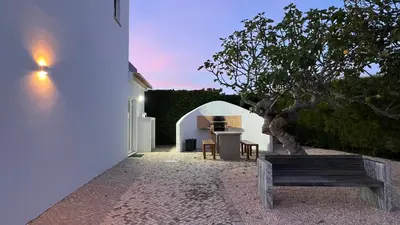 a white building with a tree and a bench at Dad's Villa in Lagos