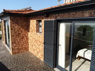 a extension to a brick house with a glass door at Villa do Italiane in Estreito da Calheta