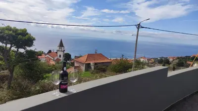 two wine glasses and a bottle of wine on a wall at Villa do Italiane in Estreito da Calheta