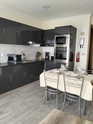 a kitchen with black cabinets and a table and chairs at Villa do Italiane in Estreito da Calheta