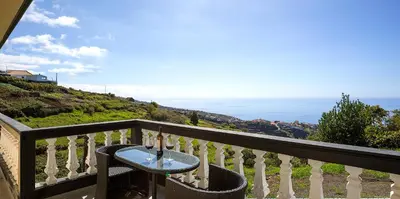 a table on a balcony with a view of the ocean at Franco's House, mar e serra in Estreito da Calheta