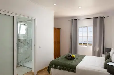 a bedroom with a bed and a glass shower at Franco's House, mar e serra in Estreito da Calheta
