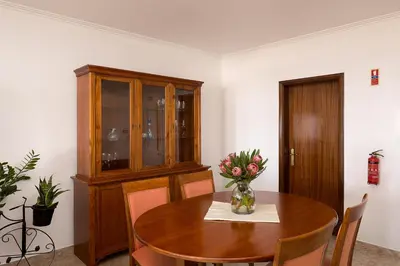 a dining room with a table with a vase of flowers at Franco's House, mar e serra in Estreito da Calheta