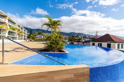 a large swimming pool with palm trees and buildings at Eden Loft by Madeira Dream Stays in Funchal