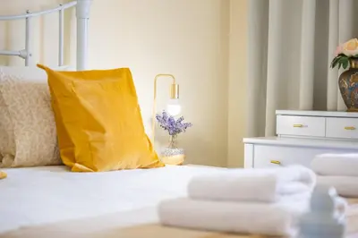 a white bed with a yellow pillow and a vase of flowers at Cantinho dos Ilhéus in Funchal