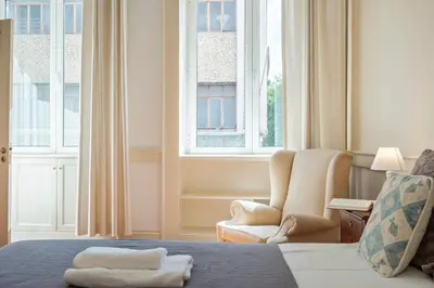 a bedroom with a bed and a chair and windows at Villa Diniz by Madeira Dream Stays in Funchal