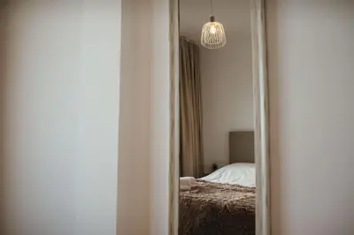 a mirror in a room with a bed and a chandelier at Cristo Rei Ocean View in Caniço
