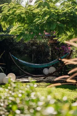 a hammock in a garden with flowers and plants at Mea Suna in Arco da Calheta