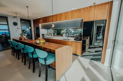 a kitchen with a wooden counter and blue chairs at Mea Suna in Arco da Calheta