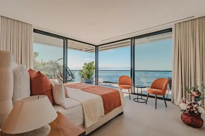 a bedroom with a bed and a view of the ocean at Mea Suna in Arco da Calheta