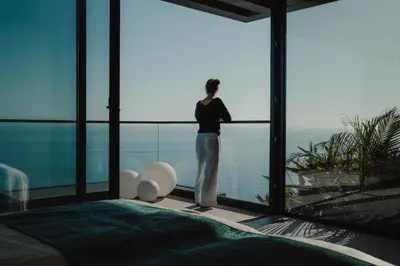 a woman standing in a room looking out of a window at Mea Suna in Arco da Calheta
