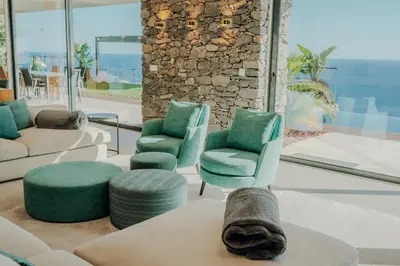 a living room with chairs and a cat laying on a table at Mea Suna in Arco da Calheta