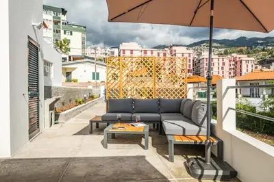 a couch on a balcony with an umbrella at Betty's Villa by ALMA Holiday Rentals in Funchal
