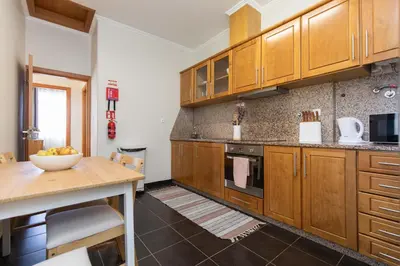 a large kitchen with wooden cabinets and a table at Casa da Jackie by Rent-a-key in Funchal