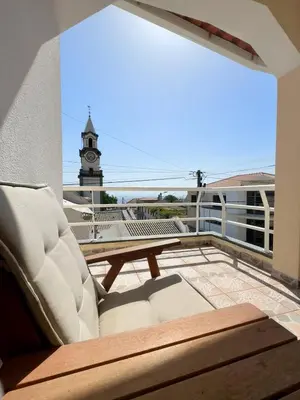 a balcony with a table and chairs and a clock tower at Casa Neves in Arco da Calheta