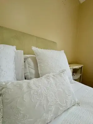 a bed with white sheets and pillows on it at Casa Neves in Arco da Calheta