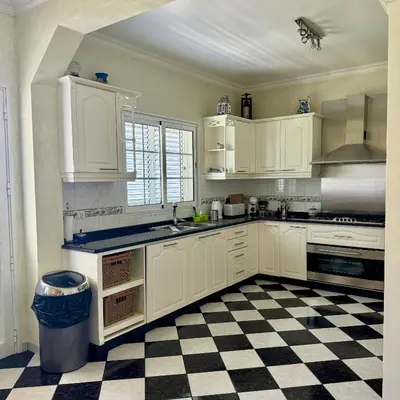 a kitchen with white cabinets and a checkered floor at Casa Neves in Arco da Calheta