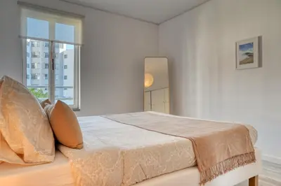 a white bedroom with a large bed with a window at Maranta House, a Home in Madeira in Funchal