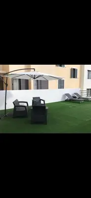 two chairs and an umbrella on a lawn in front of a building at O lagar in Câmara de Lobos