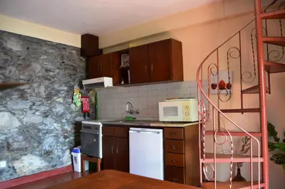 a kitchen with a white refrigerator and a stone wall at Casal São João Cottages in Fajã da Ovelha
