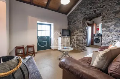 a living room with a couch and a stone wall at Casa do Maurício by GALMI in Ponta do Pargo