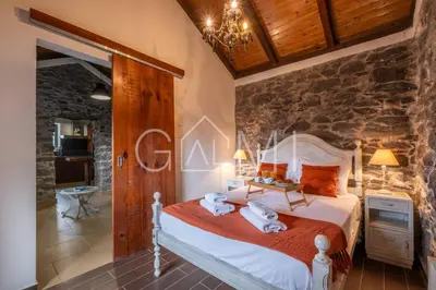 a bedroom with a bed and a stone wall at Casa do Maurício by GALMI in Ponta do Pargo