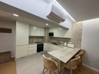 a kitchen with white cabinets and a table and chairs at Infante Home in Funchal