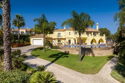 a house with a swimming pool and palm trees at Casa Amarela in Lagos