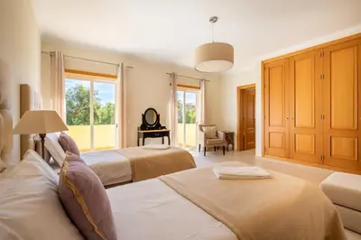 a large bedroom with two beds and a chair at Casa Amarela in Lagos