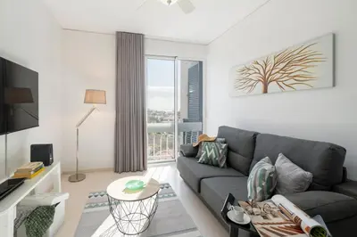 a living room with a gray couch and a large window at Apartamento América II by An Island Apart in Funchal