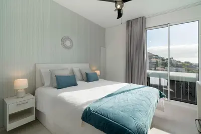 a white bedroom with a large bed and a window at Apartamento América II by An Island Apart in Funchal