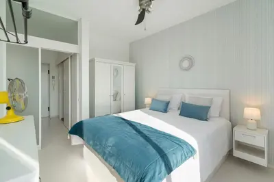 a white bedroom with a large bed with blue sheets at Apartamento América II by An Island Apart in Funchal