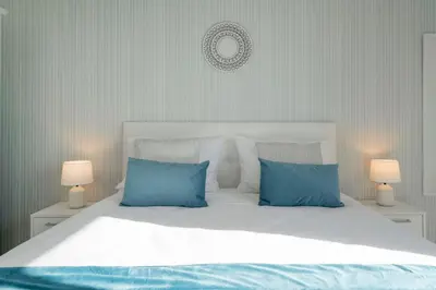 a bedroom with a white bed with blue pillows at Apartamento América II by An Island Apart in Funchal