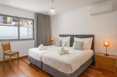 a bedroom with a large bed with a chair and a window at Villa Atlantic Sunset by Villa Plus in Funchal
