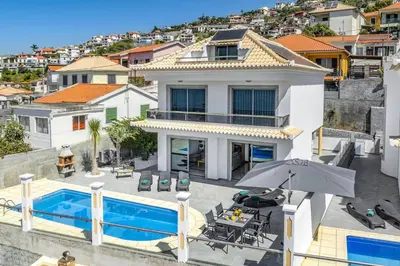 a house with a swimming pool and an umbrella at Villa Atlantic Sunset by Villa Plus in Funchal