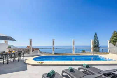 a villa with a swimming pool with a table and chairs at Villa Atlantic Sunset by Villa Plus in Funchal