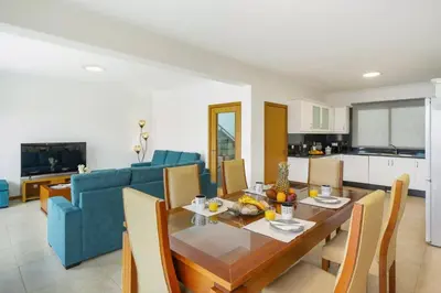 a living room with a table and a blue couch at Villa Atlantic Sunrise by Villa Plus in Funchal