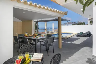 a patio with a table and chairs and a pool at Villa Atlantic Sunrise by Villa Plus in Funchal