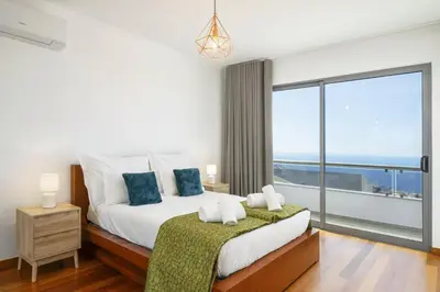 a bedroom with a large bed and a large window at Villa Atlantic Sunrise by Villa Plus in Funchal