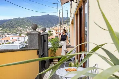 a woman sitting on a balcony talking on a cell phone at Magalhães AL by YOUR KEY MADEIRA in Machico
