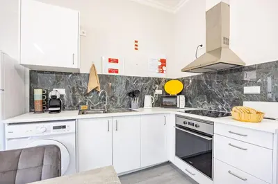 a kitchen with white cabinets and a washer and dryer at Magalhães AL by YOUR KEY MADEIRA in Machico