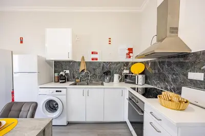 a kitchen with white cabinets and a washer and dryer at Magalhães AL by YOUR KEY MADEIRA in Machico