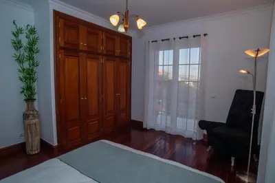 a bedroom with a bed and a chair and a window at Countesses Villa in Câmara de Lobos