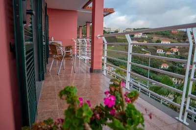 a balcony of a house with pink walls and pink flowers at Countesses Villa in Câmara de Lobos