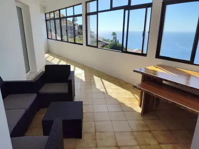 a room with a table and chairs and windows at Villa São João in Funchal