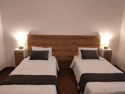 two beds in a room with two lamps on the wall at Villa São João in Funchal