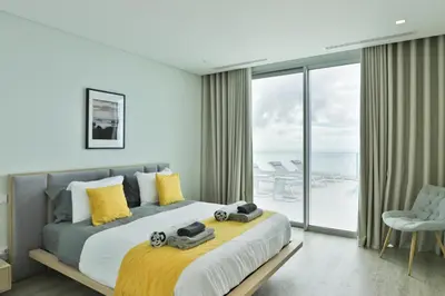 a bedroom with a large bed with yellow pillows at Villa Noelia Ocean View in Prazeres
