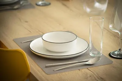 a white bowl on a plate on a table with glasses at Villa Noelia Ocean View in Prazeres